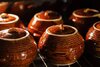 88019383-seis-vasijas-de-cerámica-de-arcilla-marrón-caliente-con-alimentos-respaldados-o-guisa...jpg