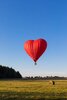 globo-aire-rojo-forma-corazon-volando-sobre-campos-pajares_82863-16.jpg