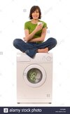 woman-in-green-top-sitting-cross-legged-on-domestic-washing-machine-B33NHB.jpg